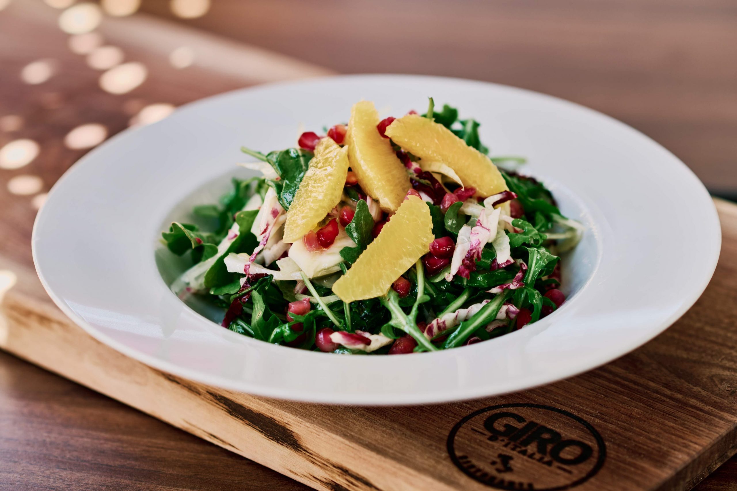 A green salad topped with colourful fruits.