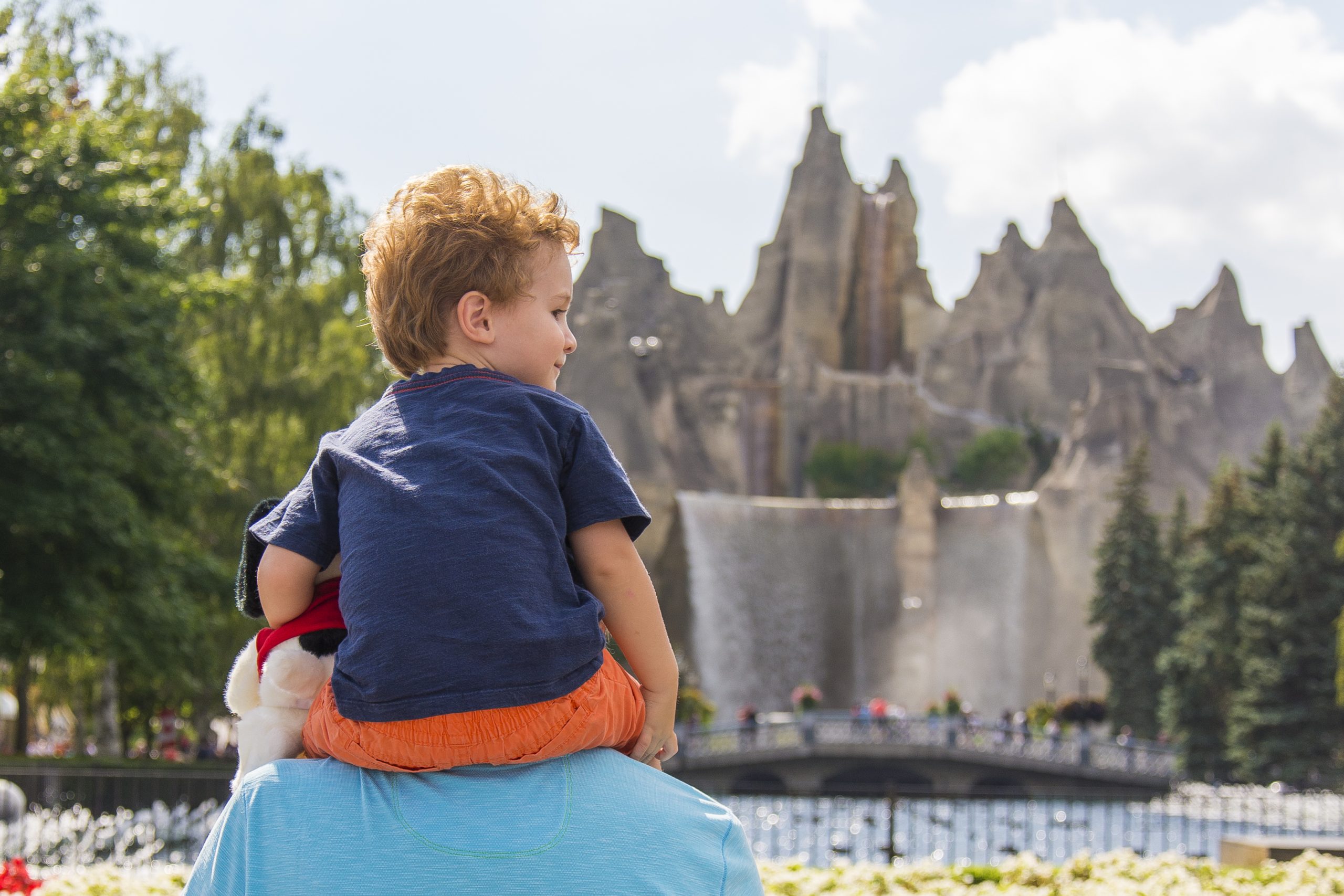 A young boy sitting on their father's shoulders with Wonder Mountain before them.